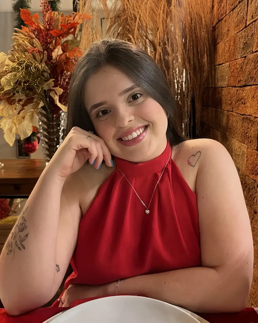 Maria Vitória, a Mavih, sorrindo com a mão no rosto